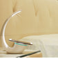 Moderne LED-Schreibtischlampe mit kabelloser Ladestation für Smartphones und platzsparendem Design.
